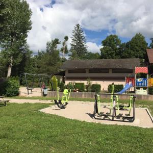 a park with a playground with two swings at camping les pêcheurs in Pont-de-Poitte