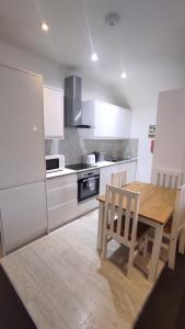 a kitchen with a wooden table and white cabinets at Staines City Centre Apartments in Staines upon Thames
