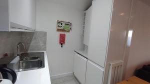 a kitchen with white cabinets and a sink at Staines City Centre Apartments in Staines upon Thames