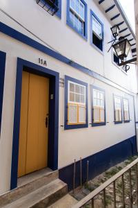 un edificio azul y blanco con una puerta amarilla en Casa do Beco - Casa Inteira no Centro de Ouro Preto en Ouro Preto