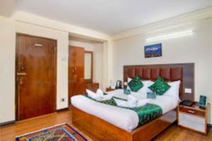 una camera da letto con un grande letto con cuscini verdi e bianchi di Hotel Muscatel BhumSang Darjeeling a Darjeeling