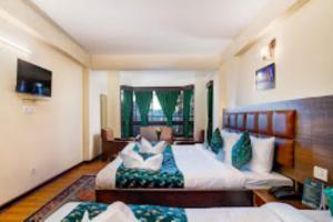 a large bedroom with two beds and a couch at Hotel Muscatel BhumSang Darjeeling in Darjeeling