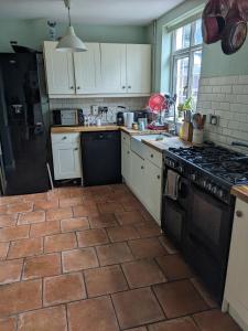 a kitchen with white cabinets and a black stove top oven at Small but bright single room not far from City Centre in Leicester