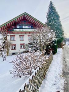 上斯陶芬的住宿－Ferienwohnung RESL - geschmackvoll renoviert & zentral im historischen Schindelhaus，雪中带围栏的建筑