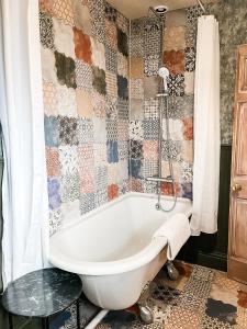 uma banheira na casa de banho com uma parede em azulejo em Belle Vue Farm B&B em Fritham