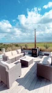 een patio met rieten meubels en een open haard bij Marsh Tide-SUPERB COASTAL home, breathtaking sea views in Wells next the Sea