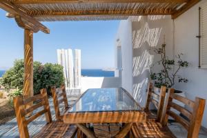a glass table and chairs on a patio with the ocean at Margarita House in Mýkonos City
