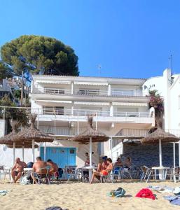 un grupo de personas sentadas bajo sombrillas en la playa en Verones 1b en Rosas