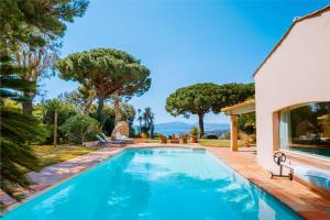 een zwembad voor een huis met bomen bij La Villa des Cades avec vue mer et piscine privée sur les hauteurs de Stre-Maxime in La Nartelle