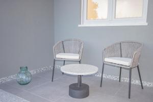 2 Stühle, ein Tisch und eine Vase in einem Zimmer in der Unterkunft Mesão Frio by Guestify in Guimarães