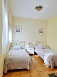 two beds in a white room with at Apartamento Rural El Ciprés Complejo la Fontanina in Mata de Alcántara