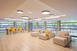 a waiting room with chairs and tables and windows at Acta CITY47 in Barcelona