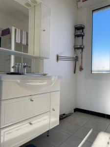 La salle de bains blanche est pourvue d'un lavabo et d'une fenêtre. dans l'établissement Appart 60 m2 séjour sur terrasse sud et 2 chambres gare Saint-Charles, à Marseille