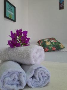 une pile de serviettes et un bouquet de fleurs violettes dans l'établissement Pousada da Sami, à Barra de São Miguel