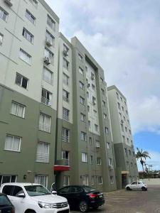 un grande edificio con auto parcheggiate di fronte di Apto aconchegante veraneio em Torres/Rs a Torres