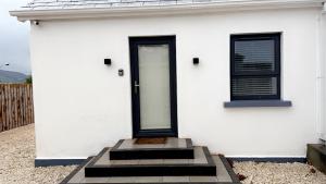 a white house with a black door and windows at Apt 3, Lisvarna House in Buncrana