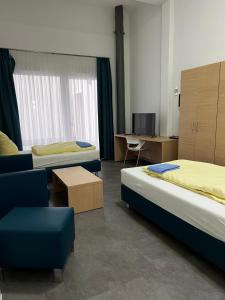 Habitación con 2 camas, silla y escritorio. en Fabella Flats Forchheim, en Forchheim