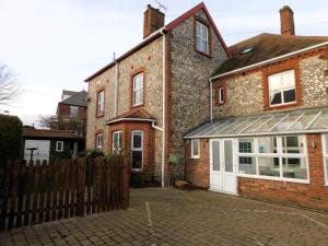 a brick house with white doors and a fence at Corner House in Sheringham