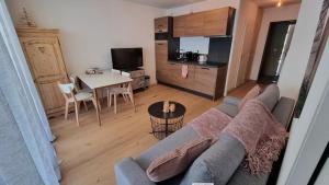 a living room with a couch and a kitchen with a table at FRGK "Charme alpin et confort moderne" in Saint-Étienne-de-Tinée
