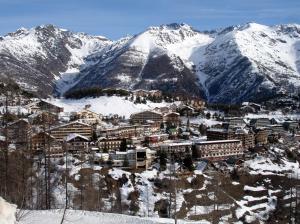 a town in the snow in front of a mountain at FRGK "Charme alpin et confort moderne" in Saint-Étienne-de-Tinée