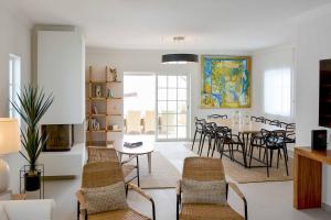 ein Esszimmer und ein Wohnzimmer mit einem Tisch und Stühlen in der Unterkunft Villa Tamara in Olhos de Água