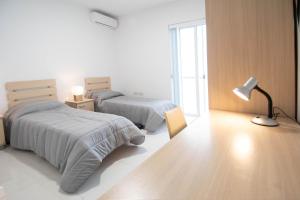 um quarto com 2 camas, um candeeiro e uma janela em Venus Apartment em Sliema