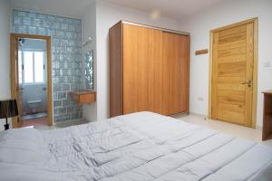 um quarto com uma grande cama branca e uma porta de madeira em Venus Apartment em Sliema