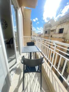 uma mesa e cadeira numa varanda com vista em Venus Apartment em Sliema