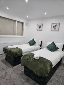 a bedroom with two beds with green pillows and a window at Charming 3-Bed House in Staines in Staines