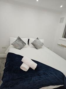 a white bed with pillows and towels on it at Charming 3-Bed House in Staines in Staines