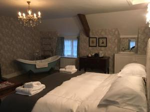 a bedroom with a large bed and a tub at Clare Cottage in Sherborne