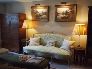a living room with a green couch and two lamps at Clare Cottage in Sherborne