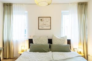 una camera da letto con un letto con lenzuola e cuscini bianchi di Bloßfeld-Apartments Geräumige Stadtoase mitten im Zentrum mit 3 Schlafzimmern, Gratis Parkplatz, W-Lan, Netflix a Jena