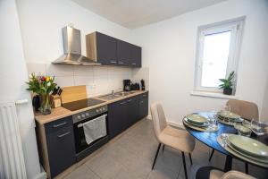 耶拿的住宿－Bloßfeld-Apartments Geräumige Stadtoase mitten im Zentrum mit 3 Schlafzimmern, Gratis Parkplatz, W-Lan, Netflix，厨房配有桌子、水槽和炉灶。