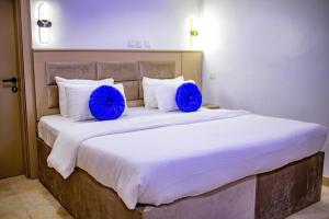 ein großes Bett mit zwei blauen Kissen darauf in der Unterkunft WELLINGTON HOTEL LIMITED in Effurun