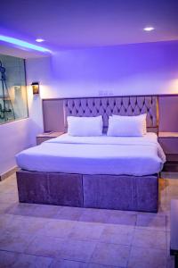 sypialnia z dużym łóżkiem i fioletową ścianą w obiekcie WELLINGTON HOTEL LIMITED w mieście Effurun