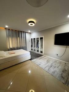 een slaapkamer met een bed en een flatscreen-tv bij Modern Home with 75” TV, 5mints from Beach & City in Dar es Salaam