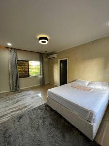 een slaapkamer met een groot wit bed en een tapijt bij Modern Home with 75” TV, 5mints from Beach & City in Dar es Salaam