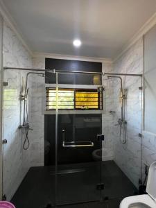 een badkamer met een douche en een glazen deur bij Modern Home with 75” TV, 5mints from Beach & City in Dar es Salaam