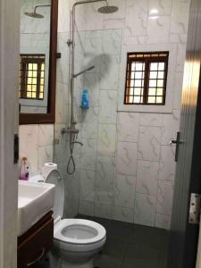 een badkamer met een douche, een toilet en een wastafel bij Modern Home with 75” TV, 5mints from Beach & City in Dar es Salaam