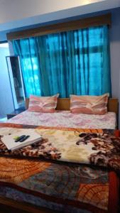 - une chambre avec un grand lit et des rideaux bleus dans l'établissement Shiv Inn Stay Darjeeling, à Darjeeling