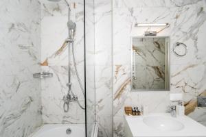 a white bathroom with a shower and a sink at Makmani Boutique Hotel in Tbilisi City