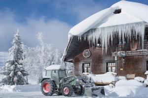 un tracteur garé devant une maison recouverte de neige dans l'établissement Ferienwohnung Kraftquelle im Wohnpark SchwarzwaldBlick, Bernau, à Bernau im Schwarzwald