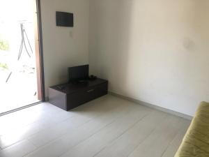 a living room with a tv on a dresser and a room with a window at Casa Vacanza Budoni Mare in Budoni +2 photos