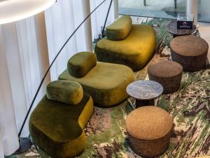 - un ensemble de chaises ottomanes et de tables dans une pièce dans l'établissement Novotel London Paddington, à Londres