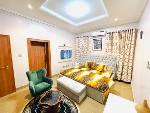 1 dormitorio con 1 cama y 1 silla verde en Avrum Homes, en Abuja