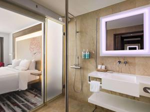 a bathroom with a sink and a shower at Novotel Jakarta Gajah Mada in Jakarta