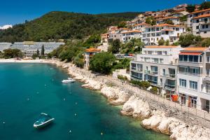 a boat in a body of water next to buildings at Boutique Hotel Adoral in Rabac