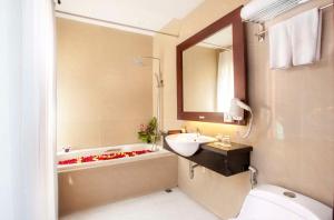 a bathroom with a sink and a tub and a toilet at Best Western Kuta Villa in Kuta