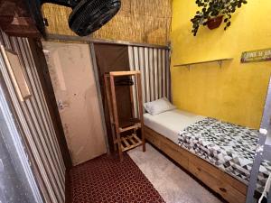 a small room with a small bed and a yellow wall at Casa du CéSaR in Fortaleza